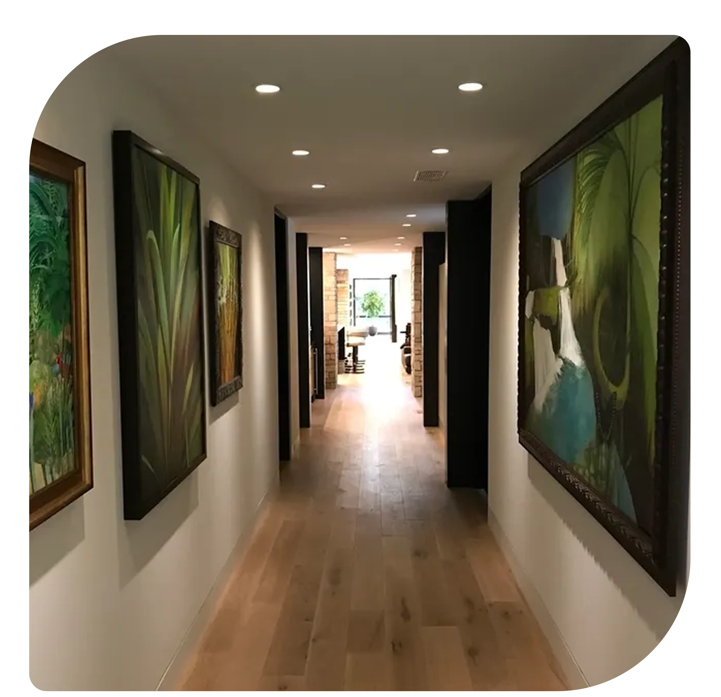 A well-lit art gallery hallway with paintings on both walls.